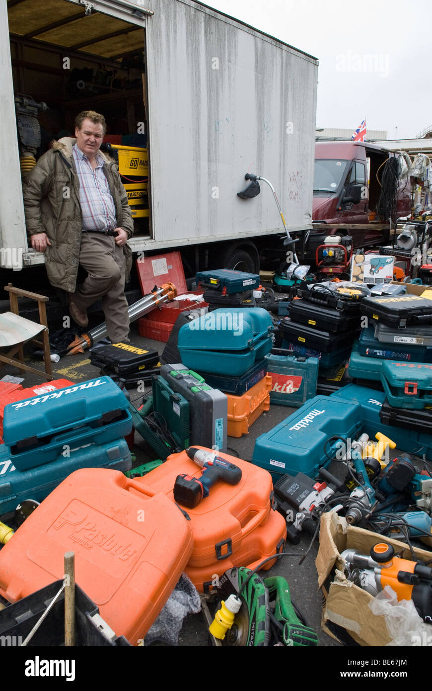 L'opérateur de marché dans le marché de Shoreditch. Vente d'outils électriques utilisés avec les détenteurs de décrochage et union jack flag dans l'arrière-plan. Banque D'Images