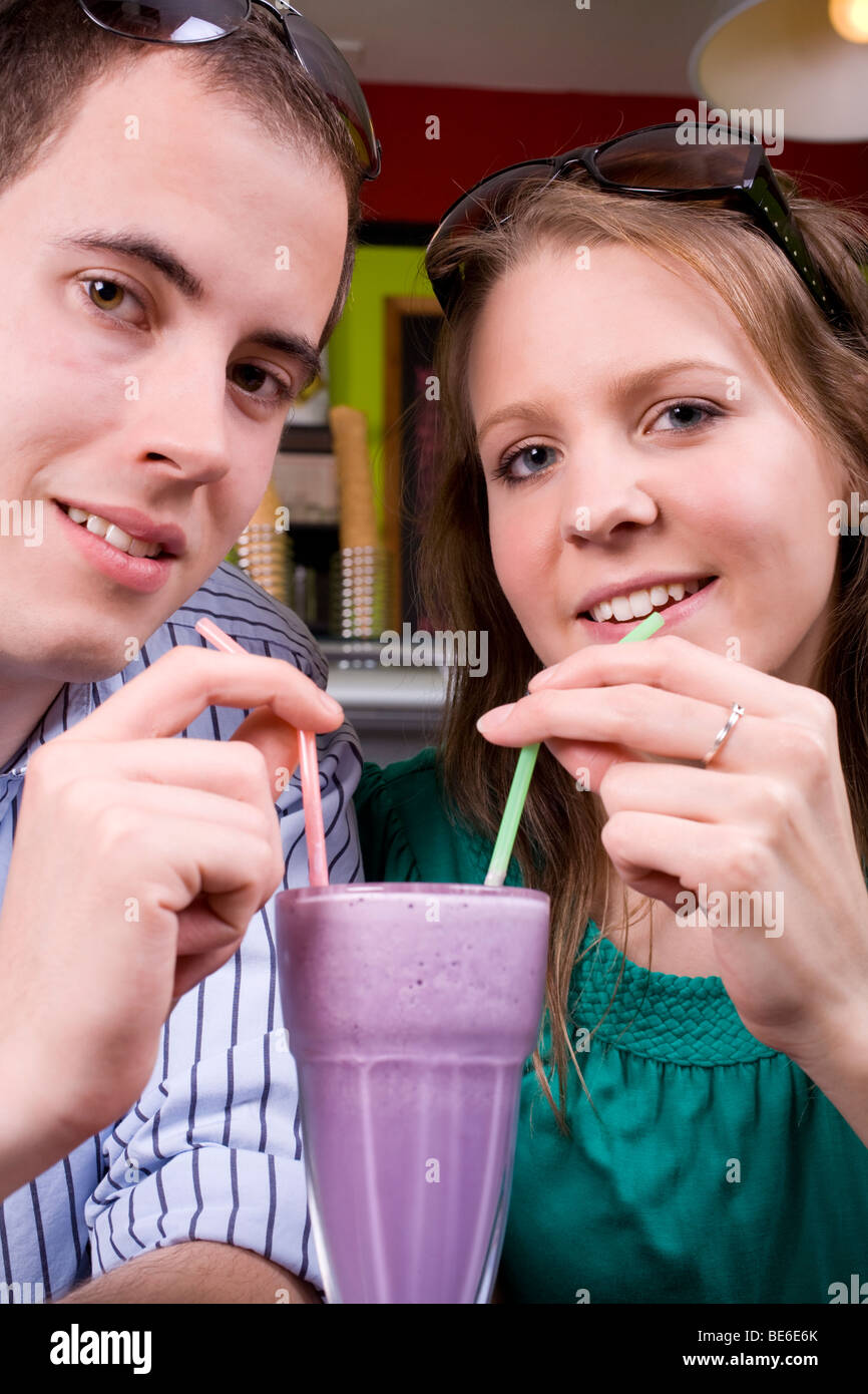Jeune couple branché partager un délicieux milk-shake dans un endroit frais et café. Banque D'Images