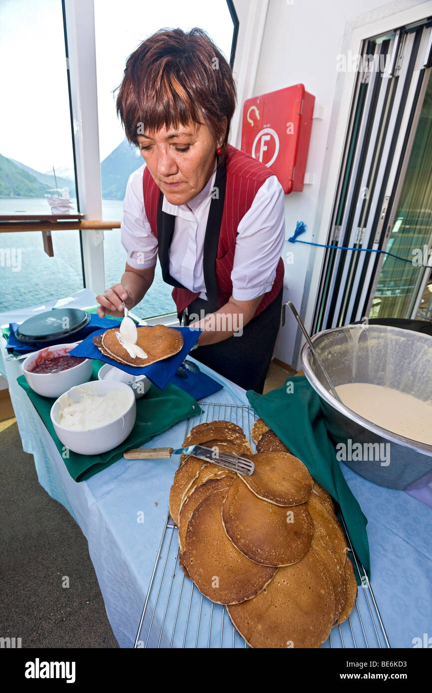 Femme membre du personnel de MS Trollfjord 'cuisiniers' vele, une crêpe traditionnelle norvégienne avec la confiture et la crème sure. Banque D'Images