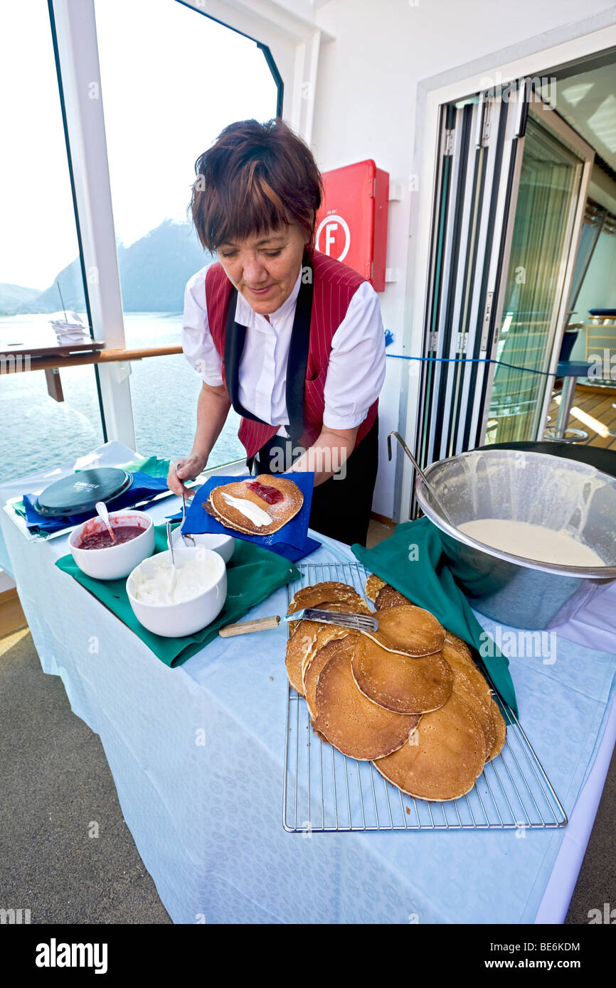 Femme membre du personnel de MS Trollfjord 'cuisiniers' vele, une crêpe traditionnelle norvégienne avec la confiture et la crème sure. Banque D'Images