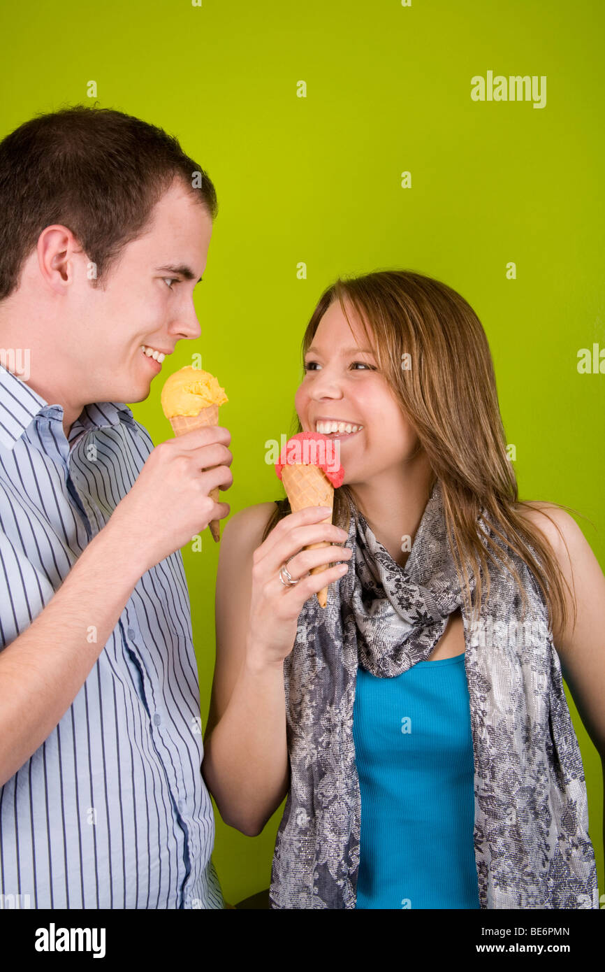 Un jeune homme et femme partageant des cornets de crème glacée. Banque D'Images