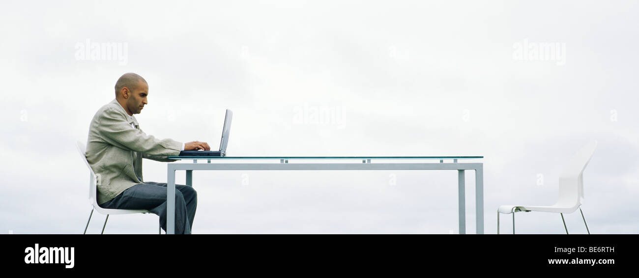 Homme assis à l'extérieur à l'aide d'un ordinateur portable Banque D'Images