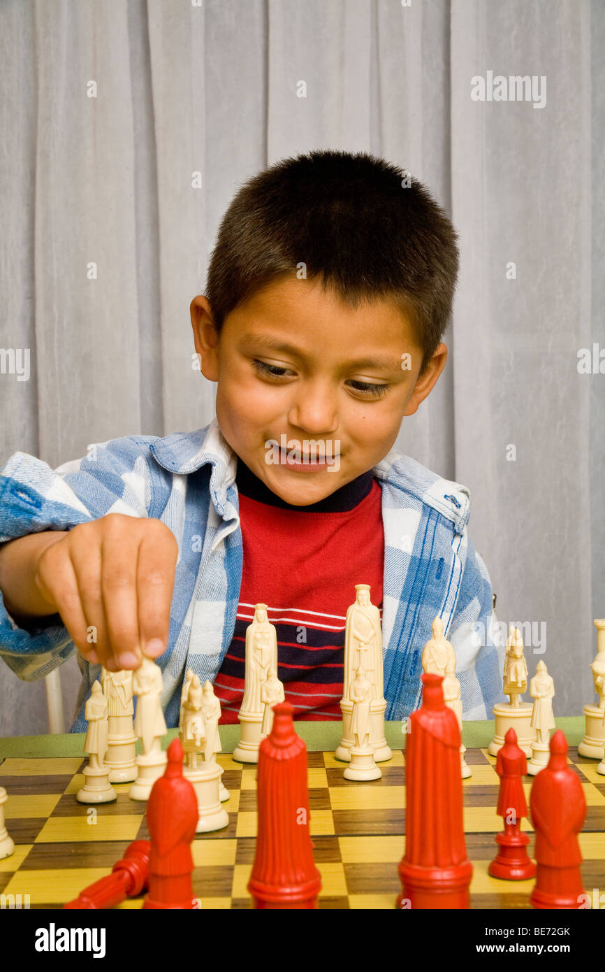 7-8 ans garçon hispanique d'apprendre à jouer aux échecs. M. © Myrleen Pearson Banque D'Images