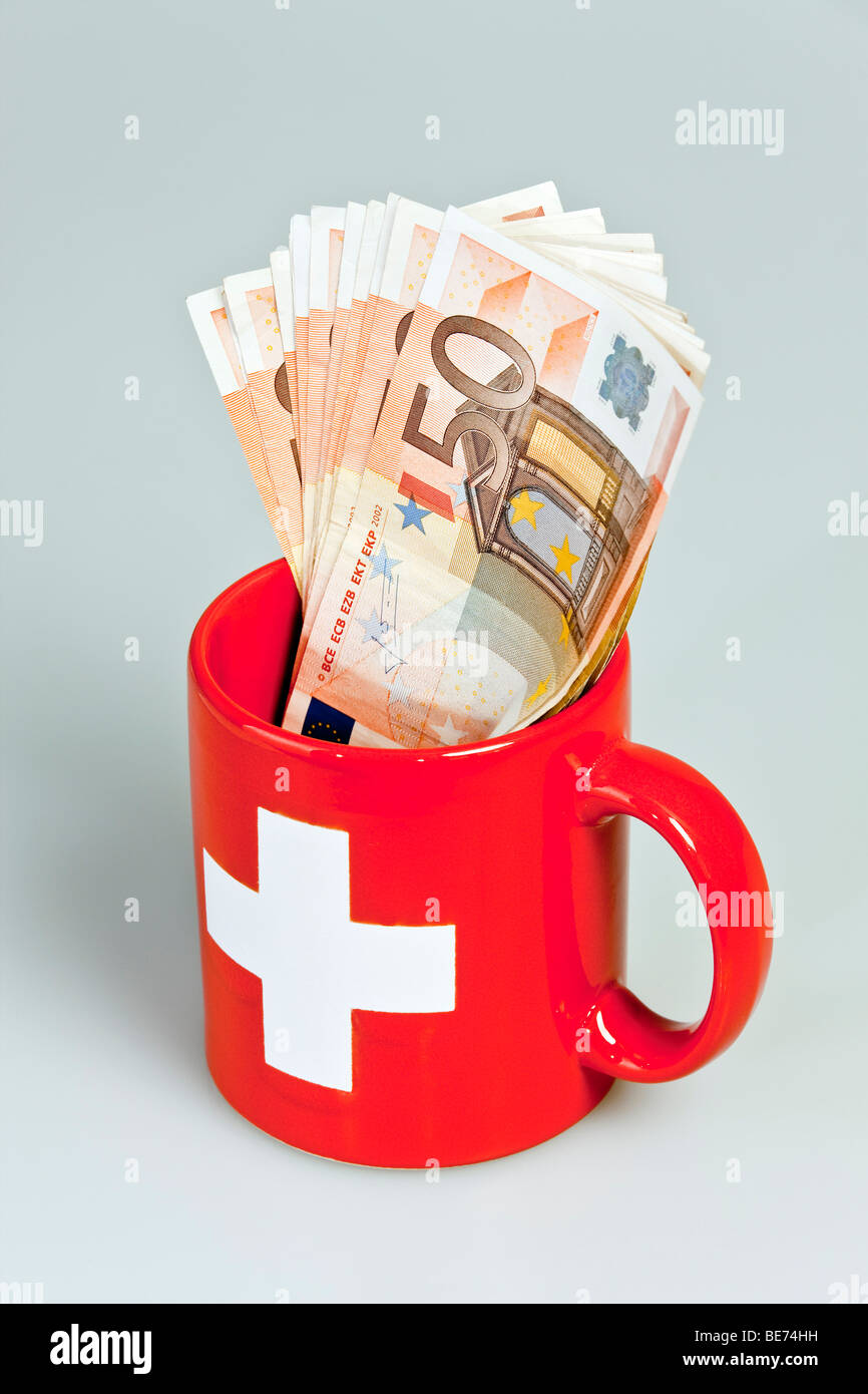 Tasse avec une croix suisse et billets en euros il Banque D'Images