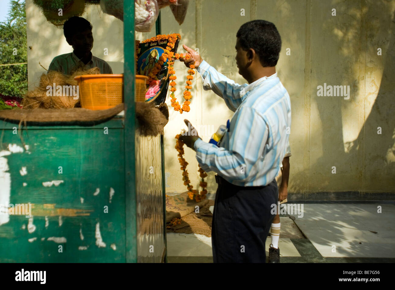 Un homme achète une guirlande d'offrir à un temple à Janakpuri, New Delhi, Inde Banque D'Images