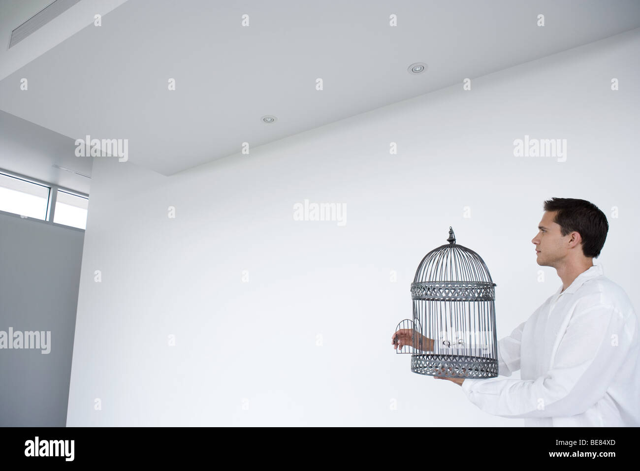 Man holding empty cage à oiseaux avec porte ouverte, side view Banque D'Images