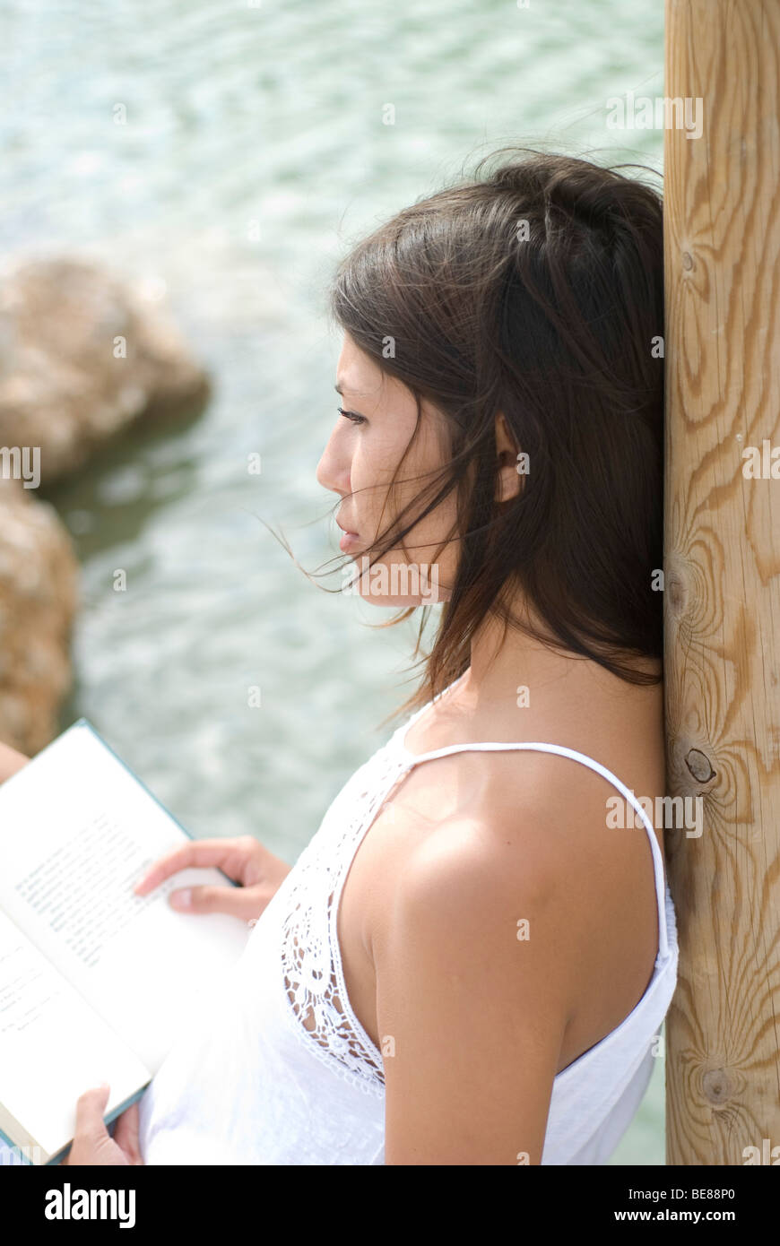 Young woman relaxing with her livre sur un lac Banque D'Images