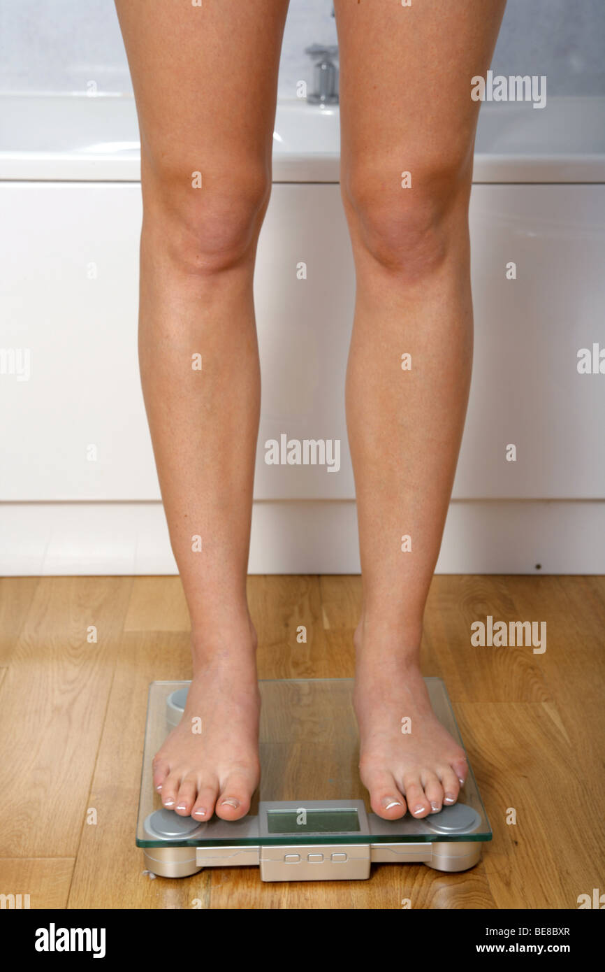 Les jambes d'une femme debout sur un pèse-personne. Banque D'Images