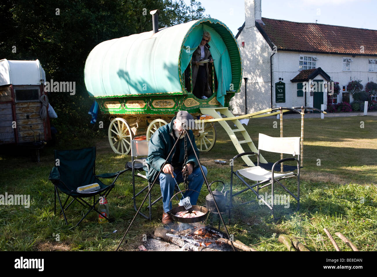 La cuisine de l'homme son petit déjeuner sur feu ouvert par sa roulotte, Taintignies vert, Suffolk, Angleterre Banque D'Images
