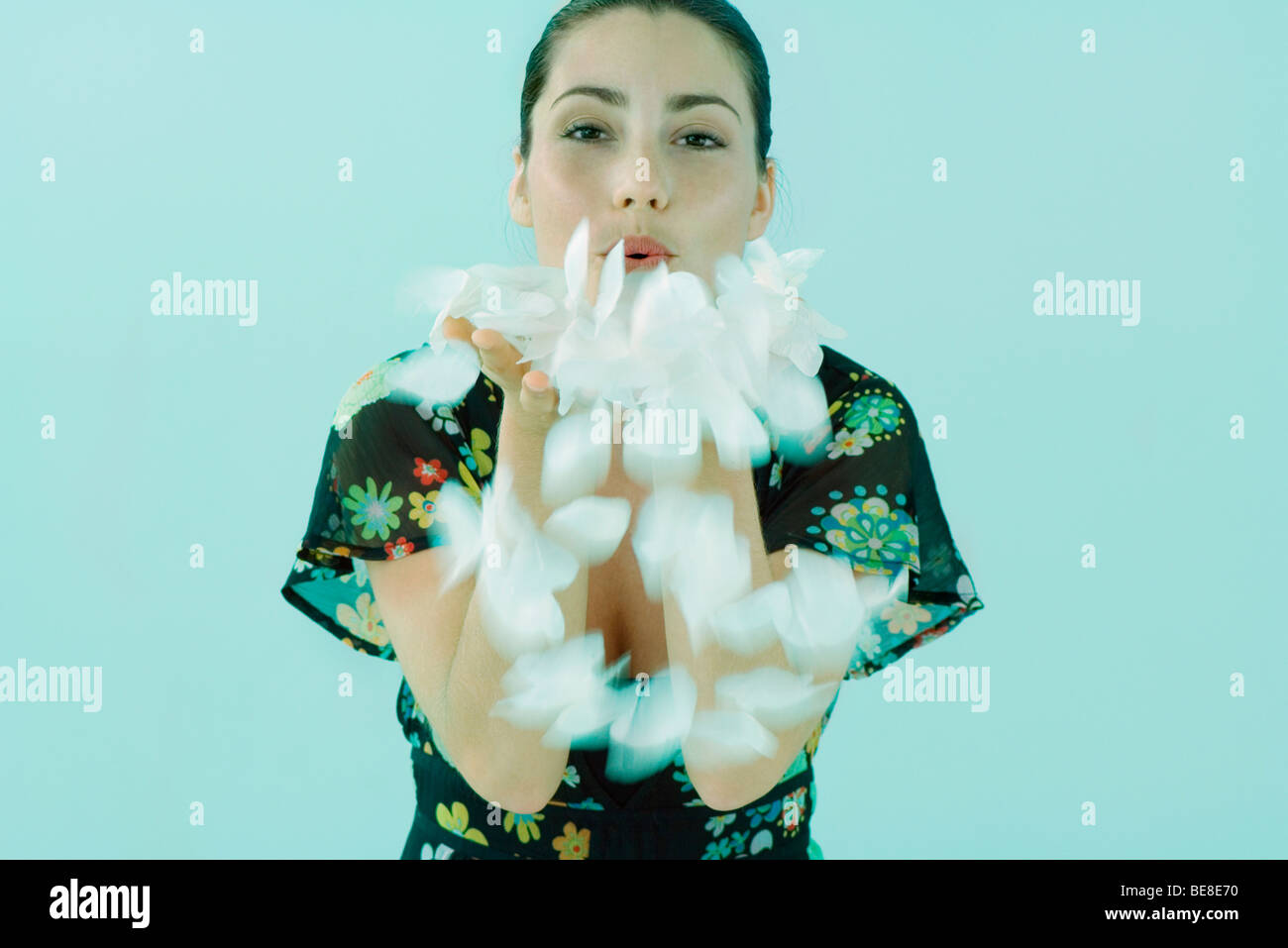Woman blowing Poignée de pétales de fleurs vers la caméra Banque D'Images