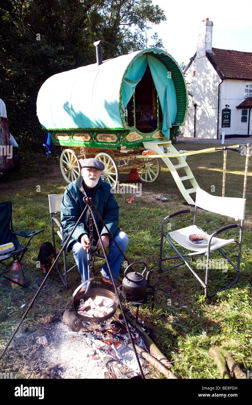 La cuisine de l'homme son petit déjeuner sur feu ouvert par sa roulotte, Taintignies vert, Suffolk, Angleterre Banque D'Images