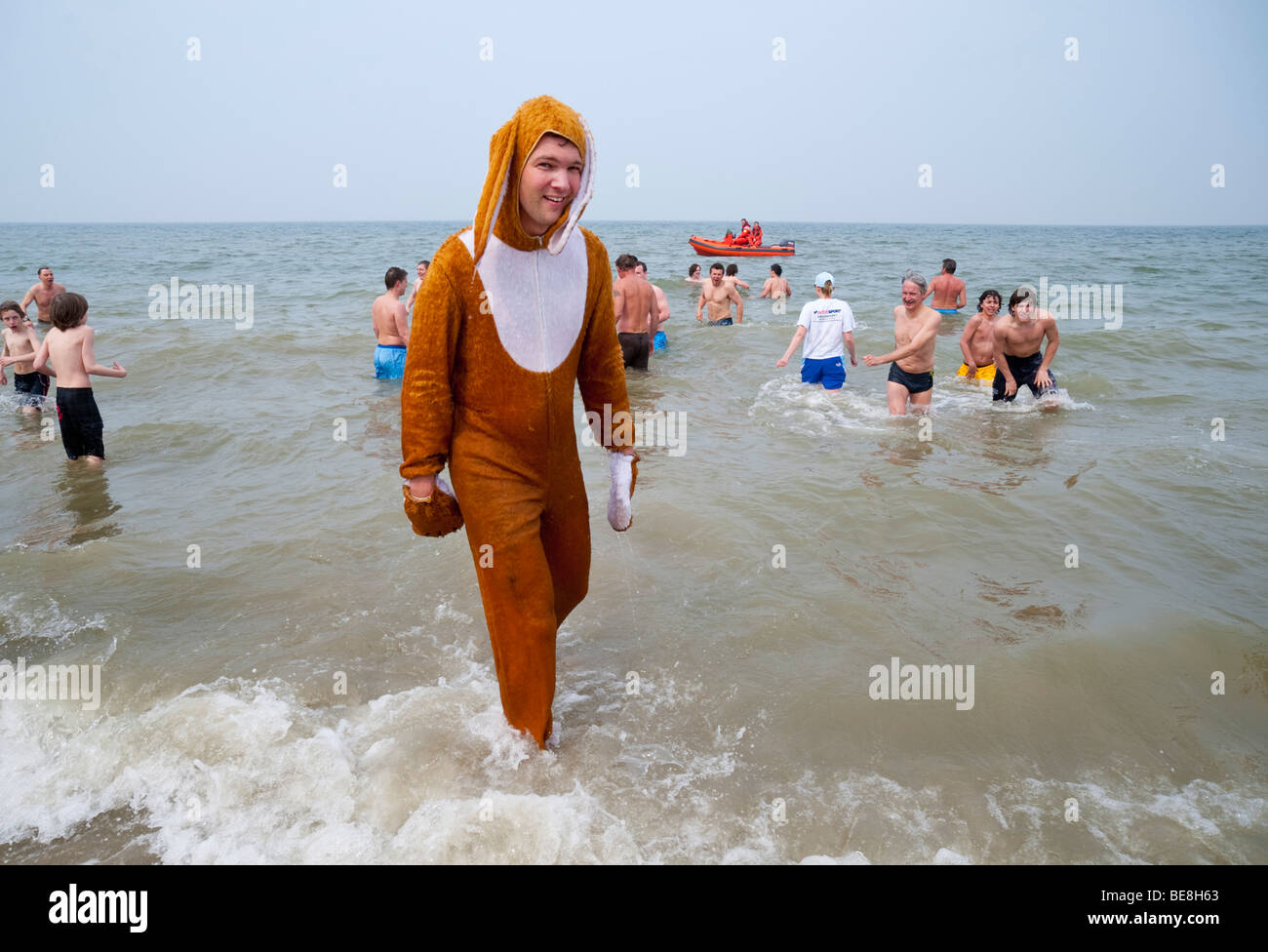 Un jeune homme habillé comme un lapin de Pâques se trouve dans la mer du Nord à l'Paasduik traditionnel de Pâques Pâques Renesse (plongée). Banque D'Images