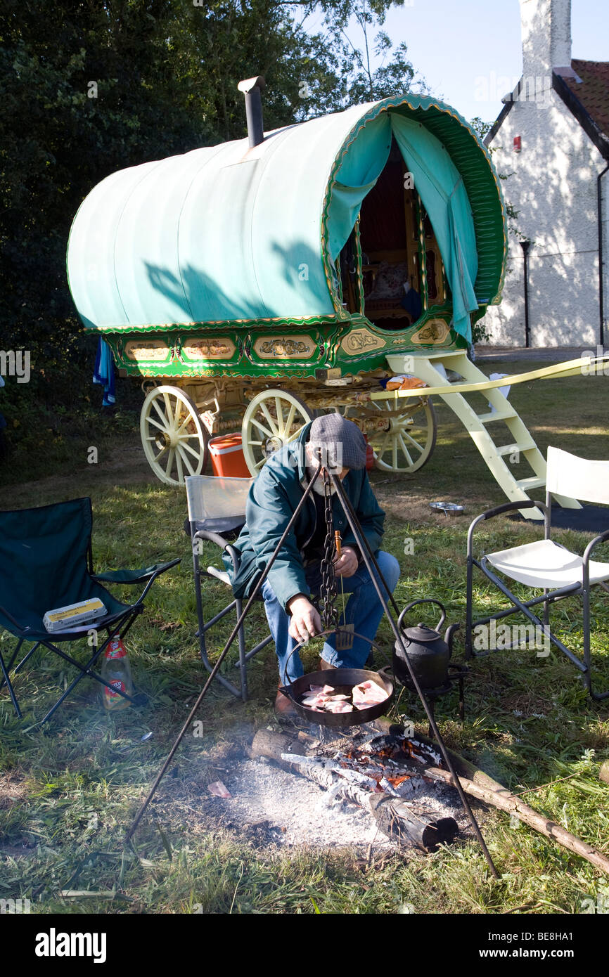 La cuisine de l'homme son petit déjeuner sur feu ouvert par sa roulotte, Taintignies vert, Suffolk, Angleterre Banque D'Images