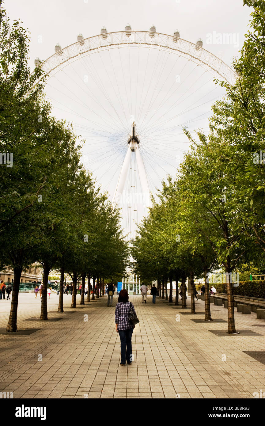Tourisme Une femme debout dans une allée d'arbres à la recherche jusqu'au London Eye. Photo par Gordon 1928 Banque D'Images