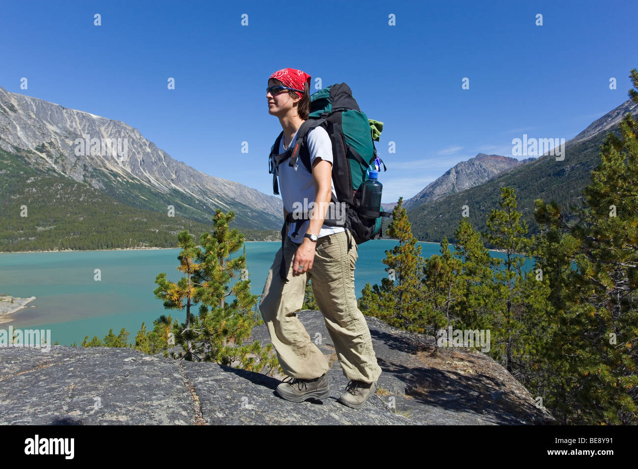 Jeune femme la randonnée, randonneur avec sac à dos, de la Piste-chilkoot historique, le col Chilkoot, lac Bennett derrière, Consul du Yukon Banque D'Images