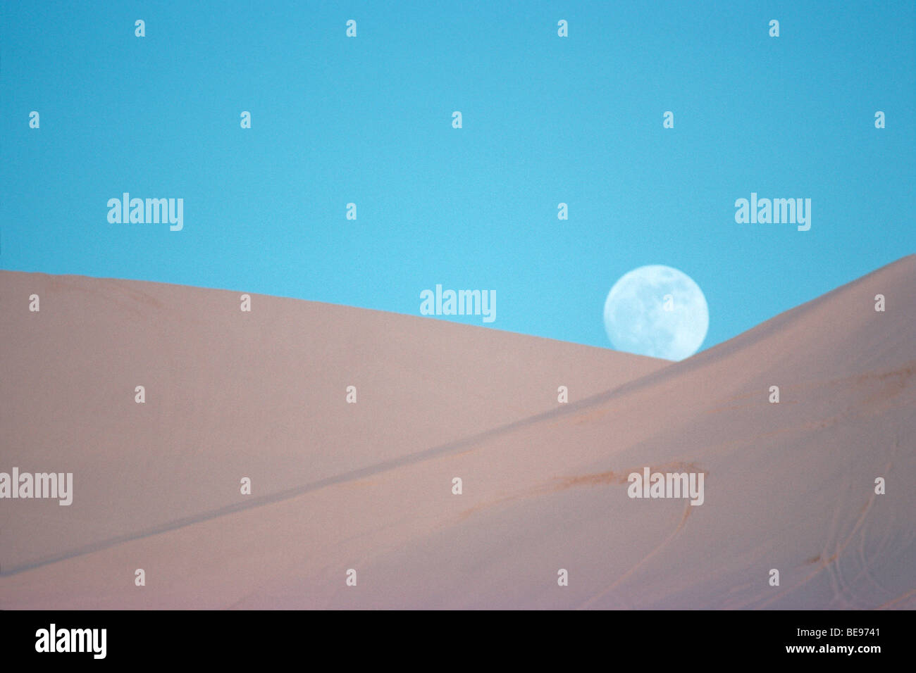 Pleine lune se lever au-dessus de dunes de sable Banque D'Images