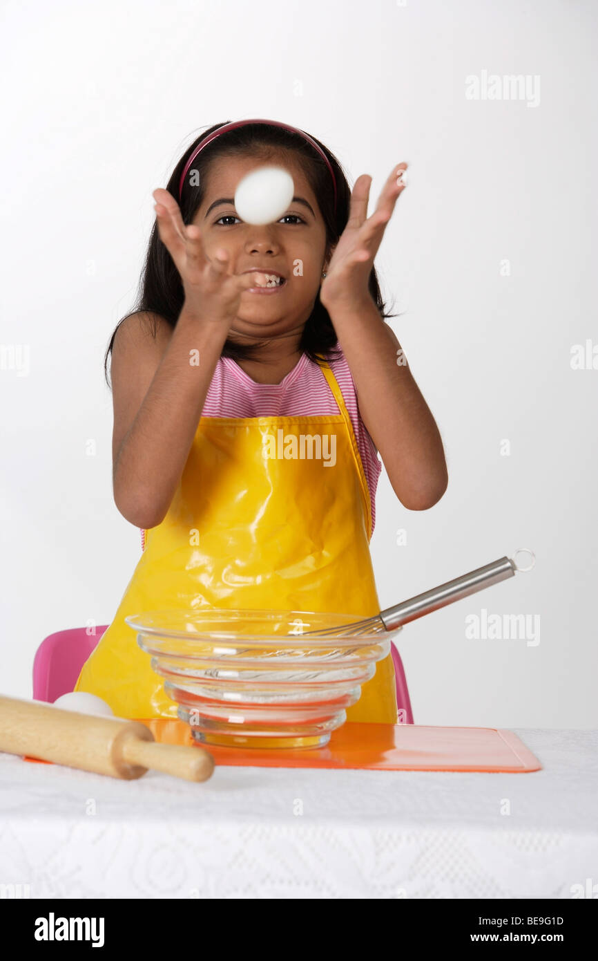 La cuisson des oeufs, le jetant fille Banque D'Images