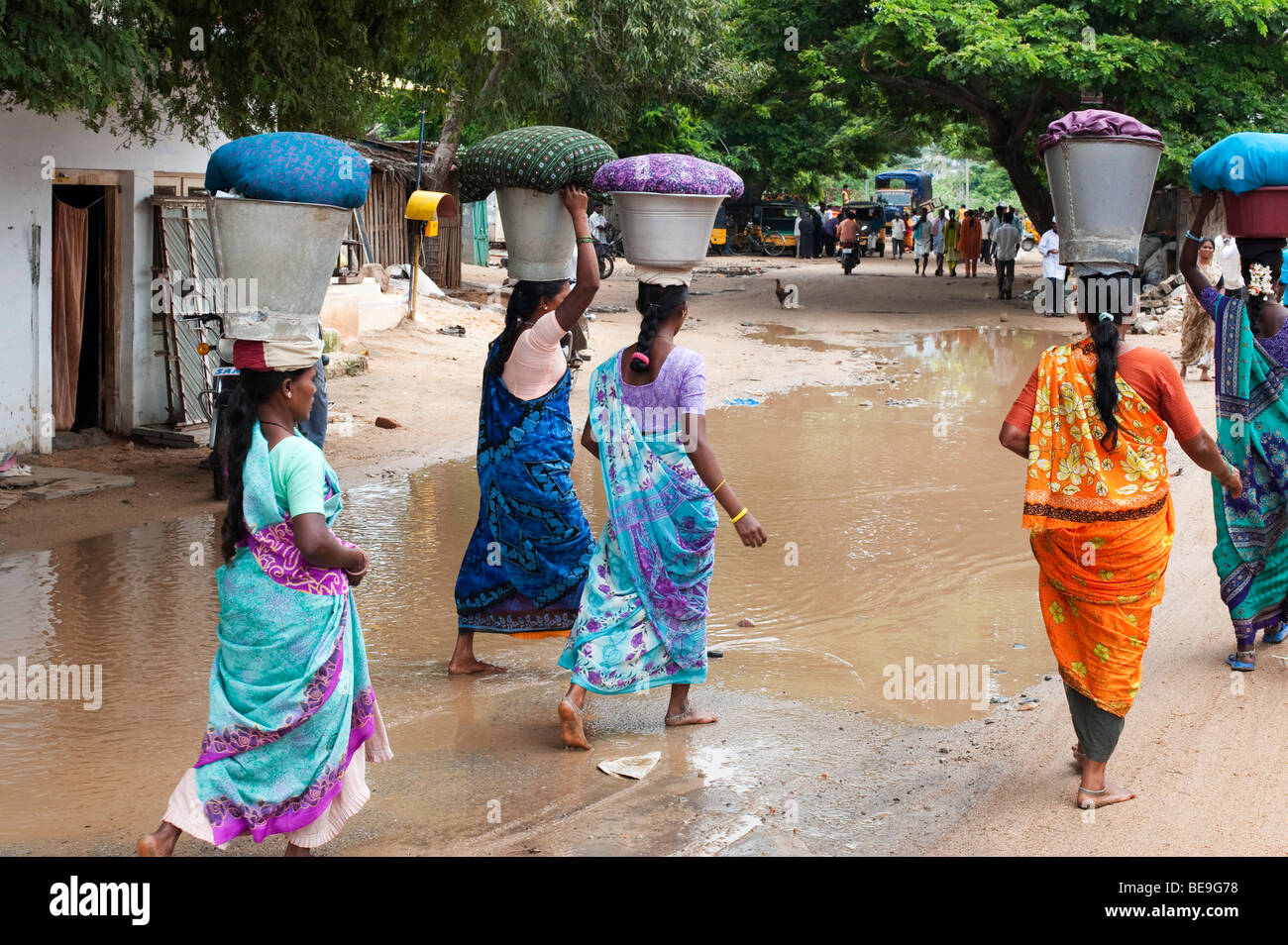 Les femmes indiennes transportant lavage des vêtements dans des seaux sur la tête il y a à travers le village de Puttaparthi, Andhra Pradesh, Inde Banque D'Images