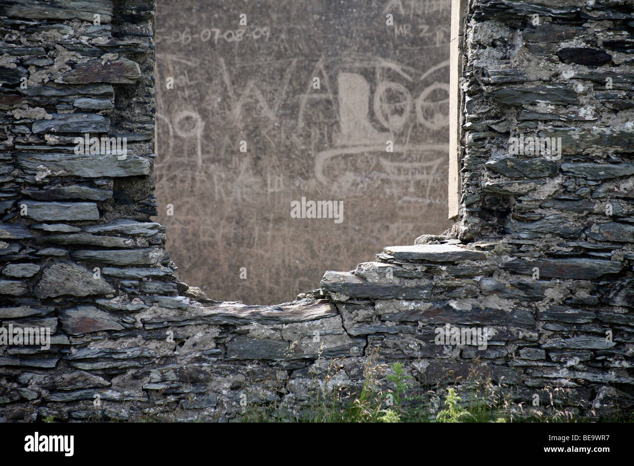 Graffiti sur un mur gris lisse encadrée par un cadre de fenêtre en ruine dans un vieux bâtiment en pierre calcaire Banque D'Images