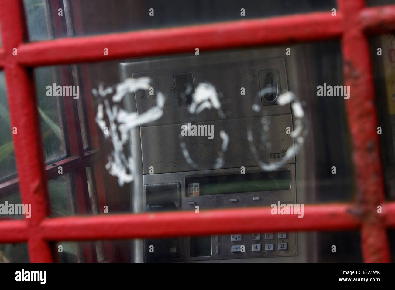 Old fashioned British Telecom téléphone rouge fort en mauvais état avec grafitti et envahis par les environs, Brighton, Royaume-Uni. Banque D'Images