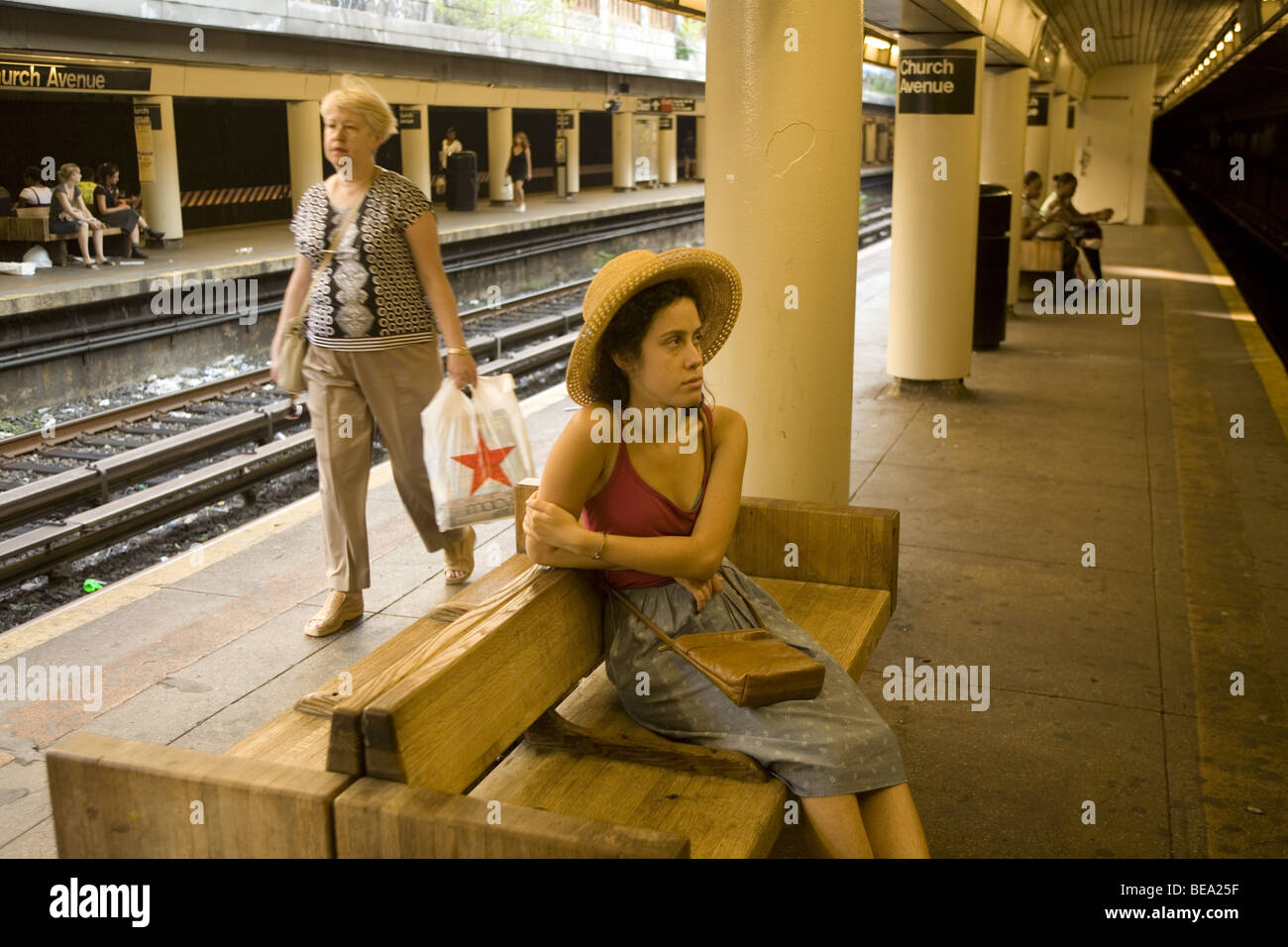 Jeune femme attend un Q train à l'église de métro Avenue à Brooklyn, New York Banque D'Images