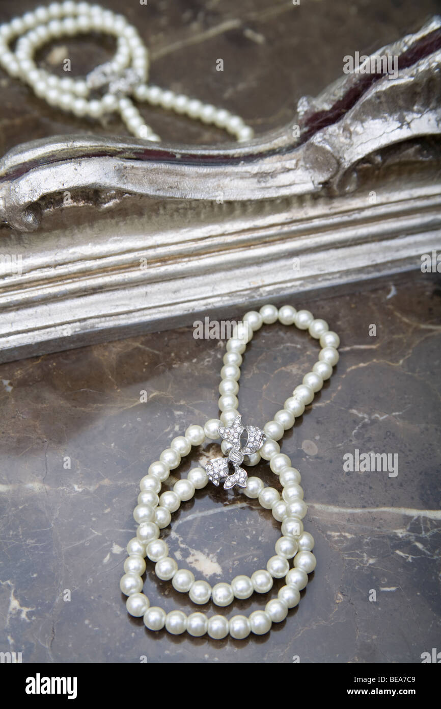 Bracelet de perles d'un blanc étincelant sur une surface en marbre d'une coiffeuse. Banque D'Images