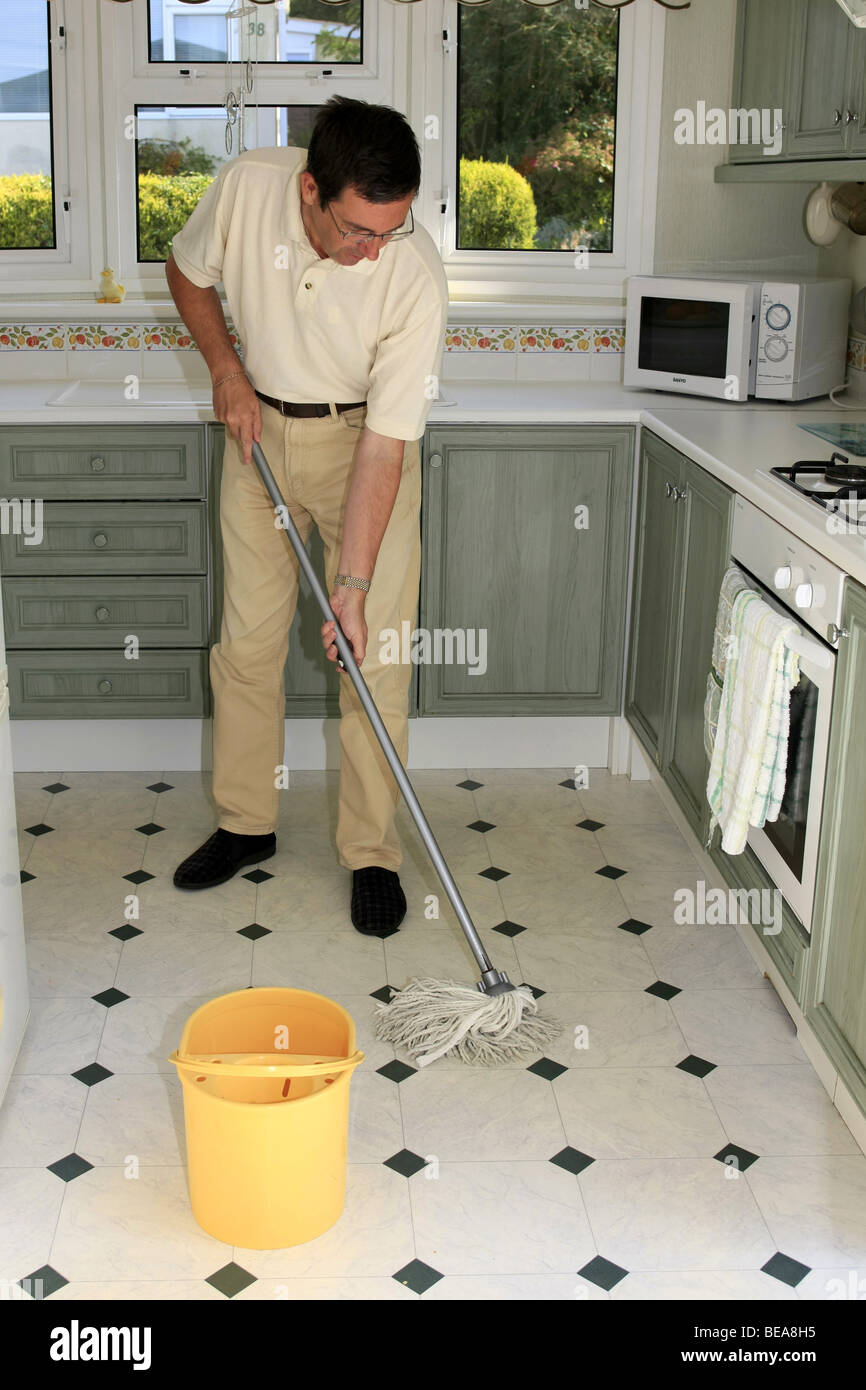 Un homme à l'aide d'une vadrouille et un seau pour nettoyer un plancher de  la cuisine Photo Stock - Alamy