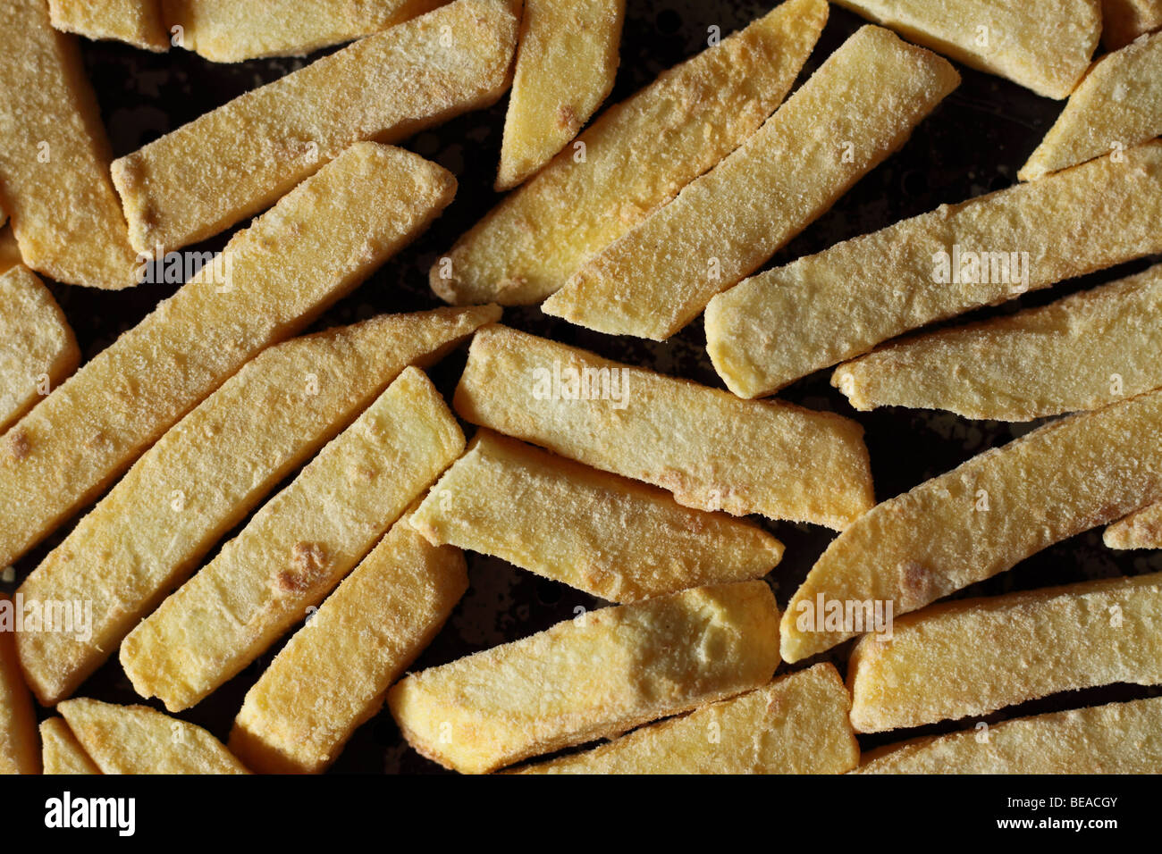 Plus de chips de pommes de terre pré cuits congelés en copeaux sur une plaque de cuisson pour la cuisson Banque D'Images