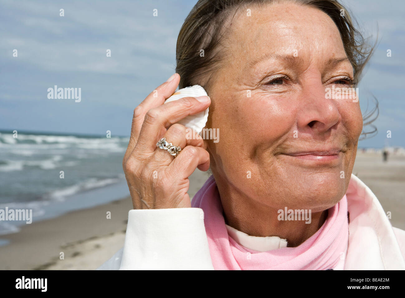 A senior woman avec un coquillage à son oreille Banque D'Images