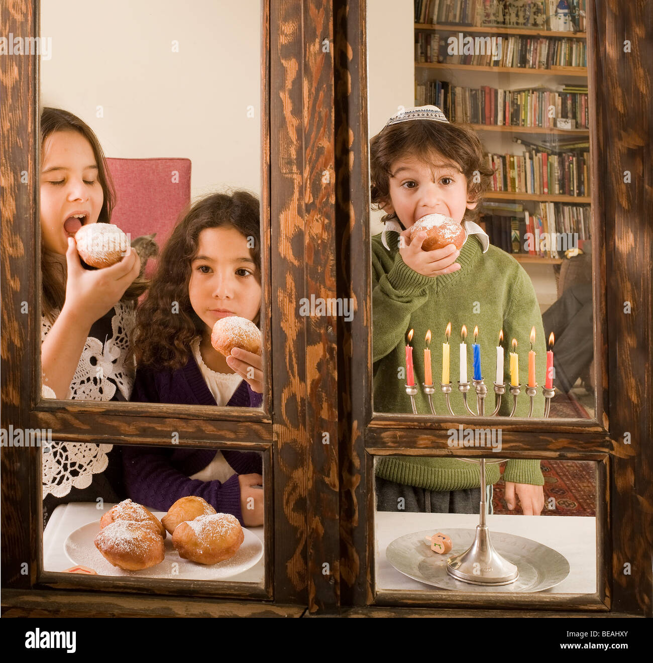 Les enfants en face d'une Hanukkia traditionnel jelly donut dans manger Hanukka Banque D'Images