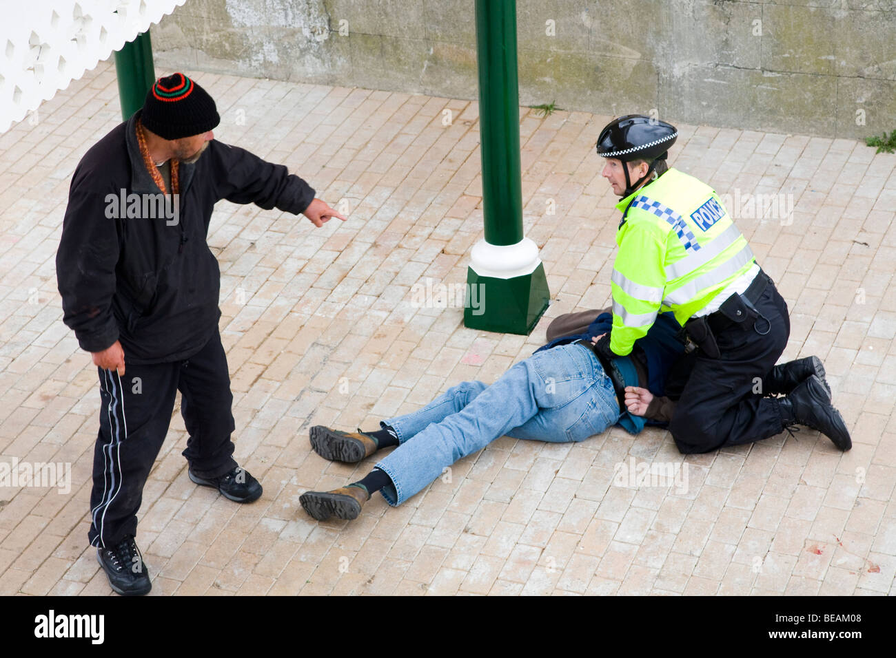 Un policier à l'arrestation d'un homme tandis que son ami ivre soutient avec lui. Banque D'Images