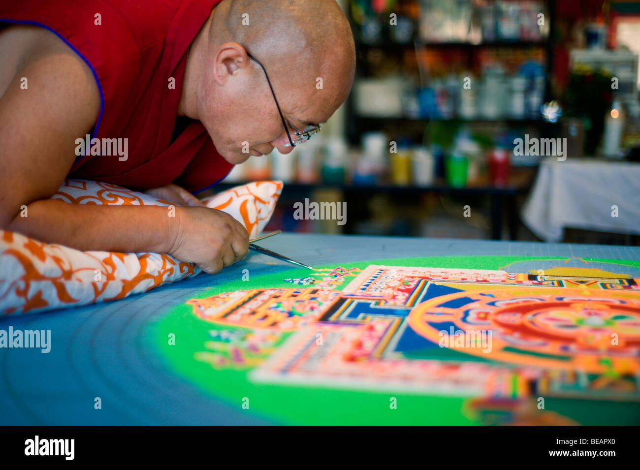 Moine tibétain Tsering VenoDhondup travaille avec soin sur un mandala de sable coloré dans la région de Ruidoso, Nouveau Mexique. Banque D'Images