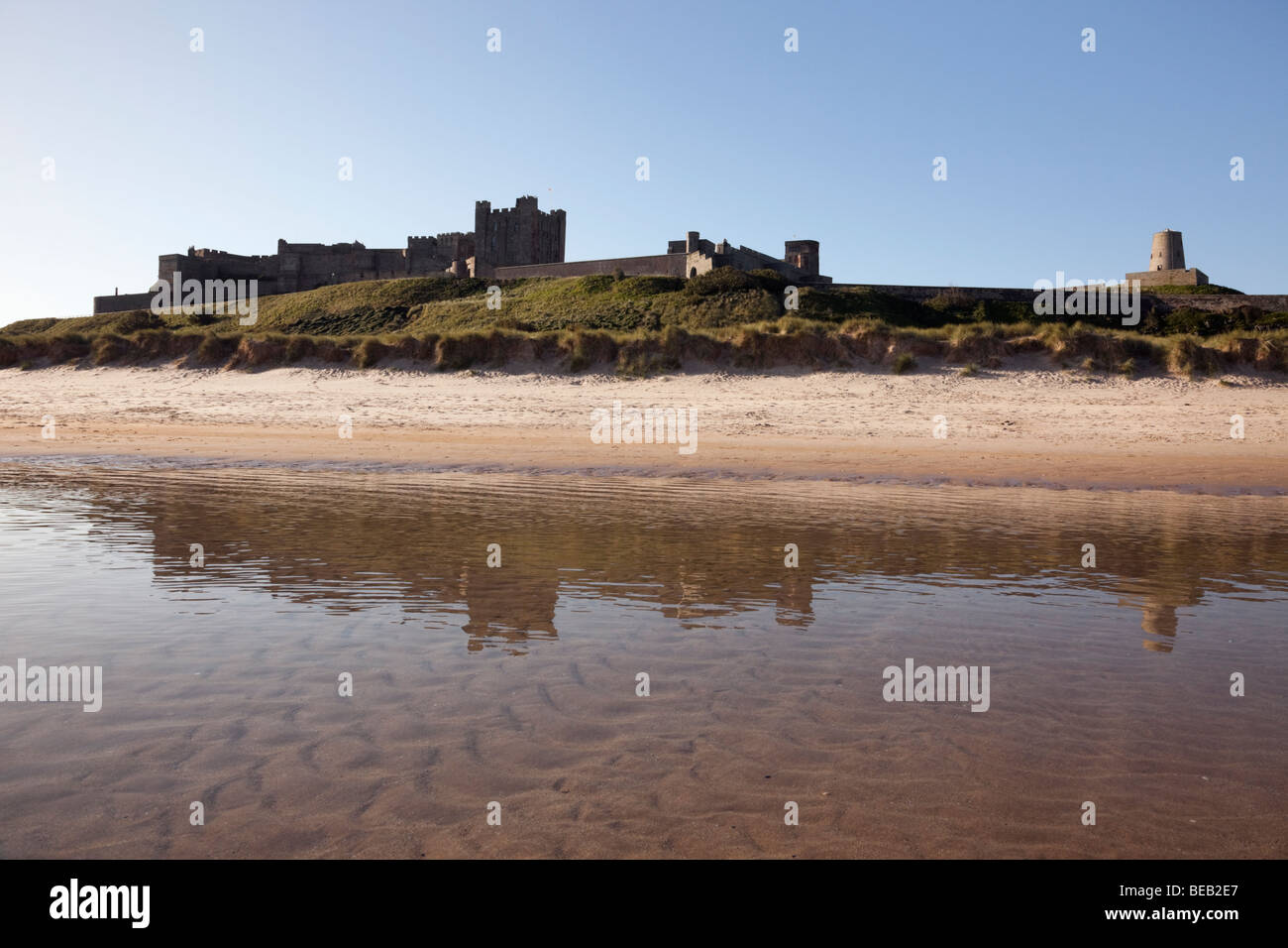 , Bamburgh Northumberland, England, UK, Europe. Château de Bamburgh reflétée dans la mer sur l'estran de la plage Banque D'Images