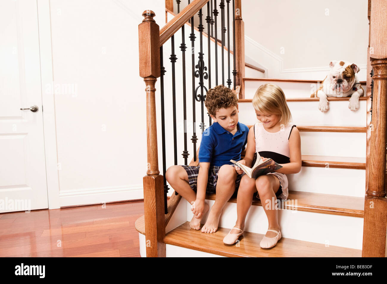 Garçon et une fille assise sur un escalier et la lecture d'un livre Banque D'Images