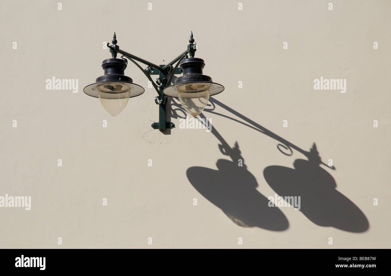 L'éclairage des rues deux lampes électriques jettent une ombre sur un mur de couleur claire Banque D'Images