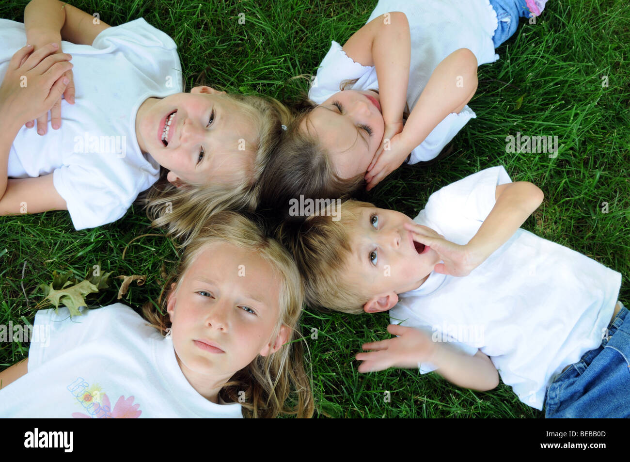 Enfants jouant sur l'herbe montrant différentes expressions Banque D'Images