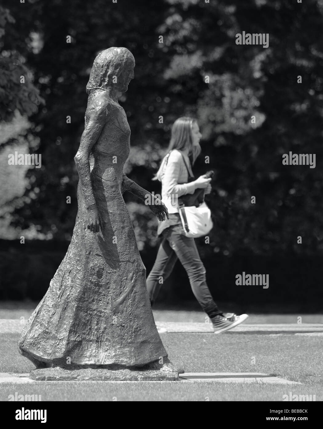 Une fille qui marche passé une sculpture par Elisabeth Frink fait écho à la pose de la sculpture. Banque D'Images