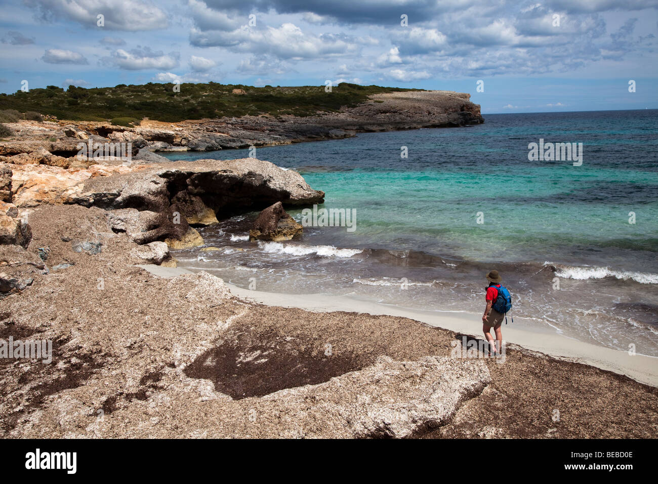 Femme randonneur sur plage avec des algues échouées sur la Cala s'Algar Majorque Espagne Banque D'Images