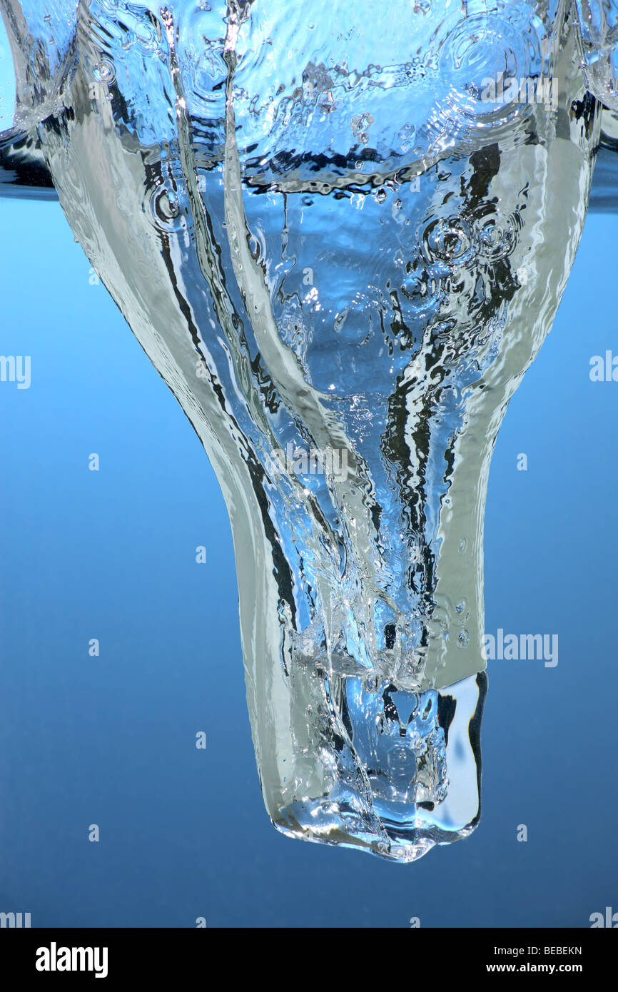 Un cube de glace tomber à l'eau Banque D'Images