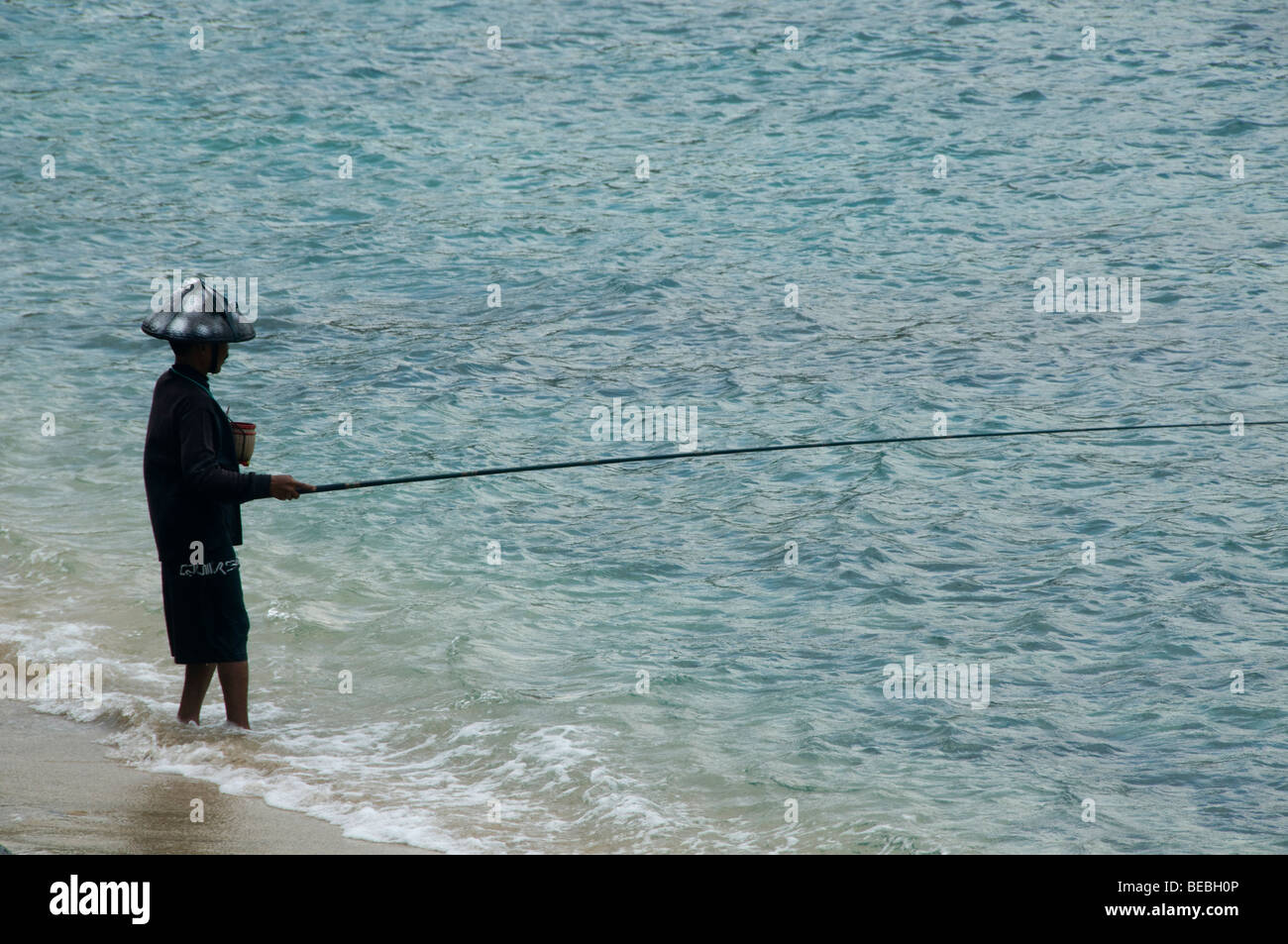 Pêcheur solitaire se dresse dans la mer à Bali en Indonésie Banque D'Images