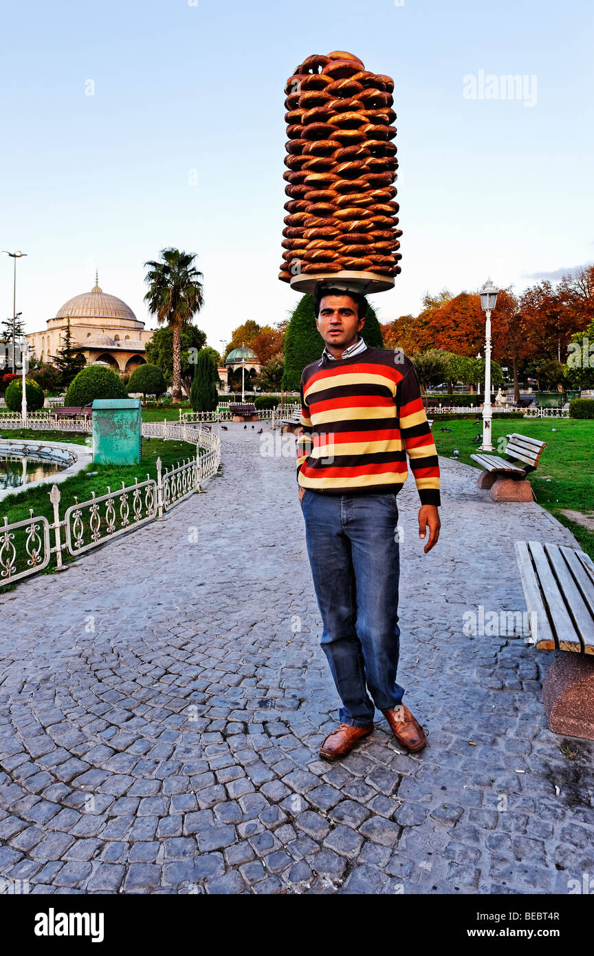 Tôt le matin dans le quartier de Sultanahmet à Istanbul. Un jeune homme turc porte une livraison de pain fraîchement cuit au four - simit rouleaux. Banque D'Images