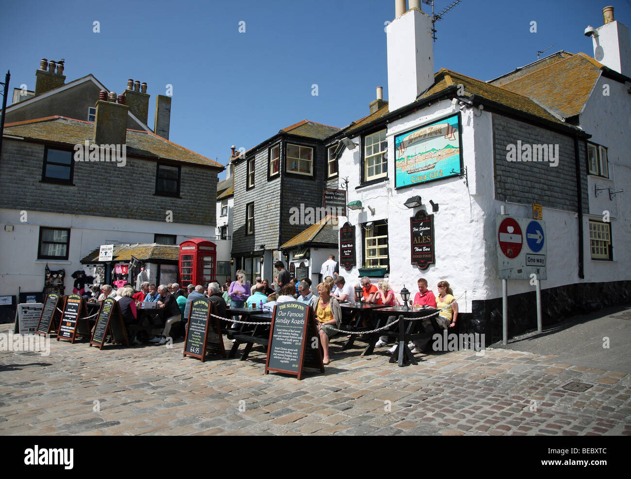 Les gens boire et manger à l'extérieur du Sloop Inn pub sur le front de mer à St Ives, Cornwall, Angleterre Banque D'Images