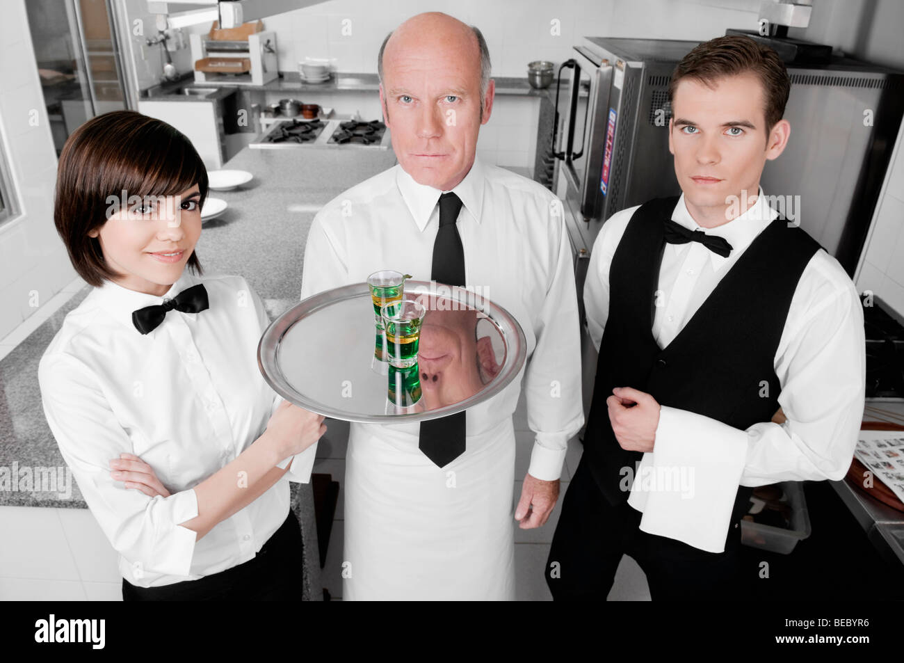 Deux serveurs et une serveuse debout dans la cuisine Banque D'Images
