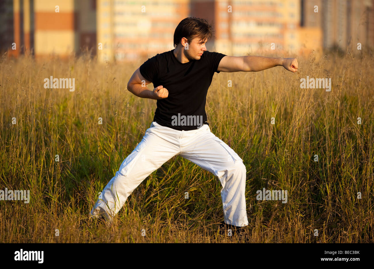 Jeune homme athlétique formation art martial. Coucher du soleil lumière rouge. Banque D'Images