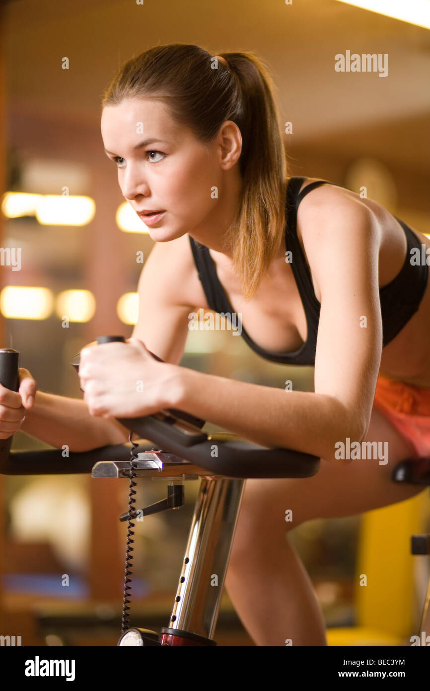 Jeune femme à l'aide de remise en forme vélo. Banque D'Images