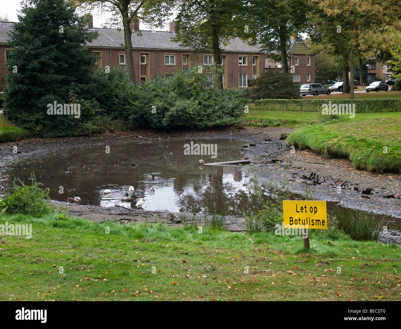 Étang dans un parc de Vught avec de très faibles niveaux d'eau et le botulisme panneau d'avertissement. Vught, Noord Brabant, Pays-Bas Banque D'Images