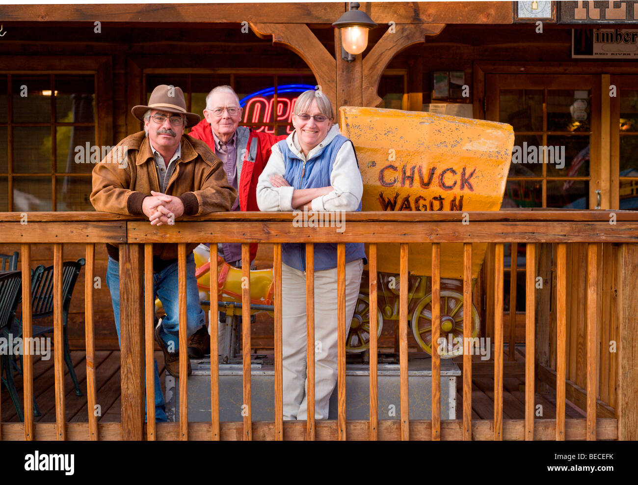 Trois touristes lounge sur le porche du bois restaurant à Red River, Nouveau Mexique. Banque D'Images