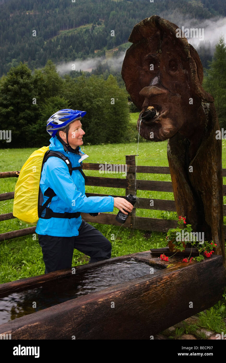 Vélo de montagne femelle remplissage sa bouteille d'eau, Styrie, Autriche Banque D'Images