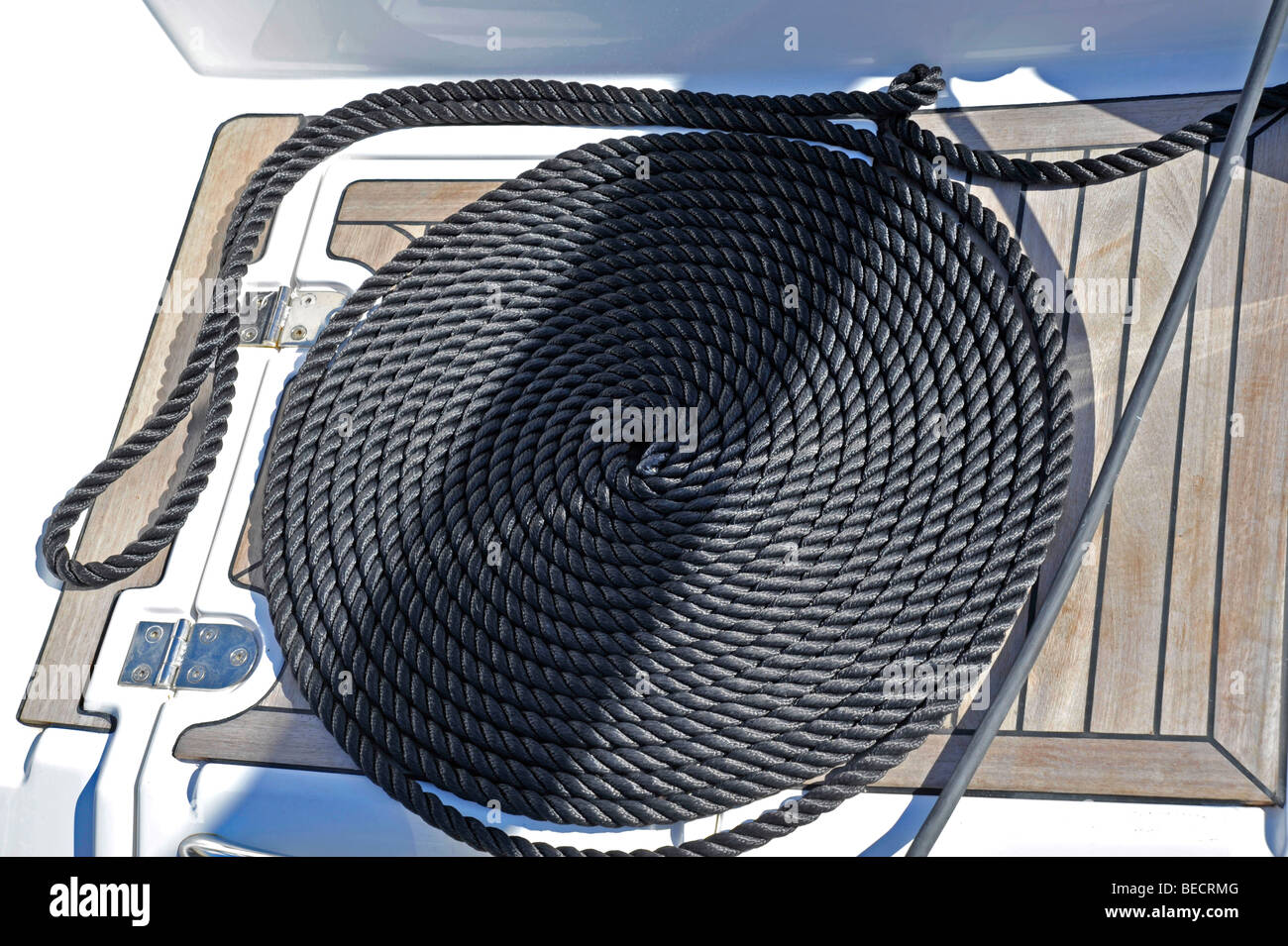Amarre enroulée sur le pont en teck de yacht à voile Banque D'Images