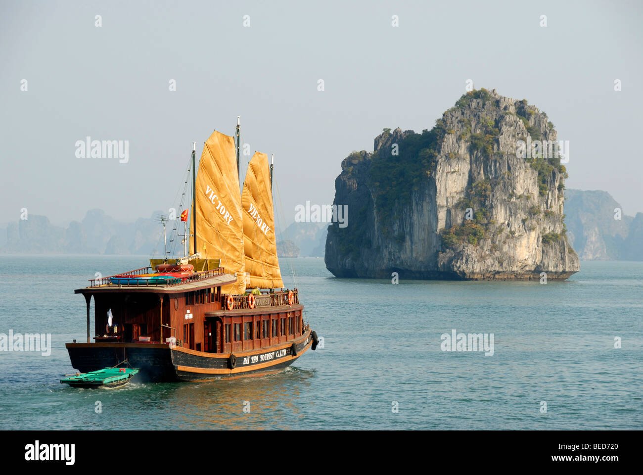 Bateau à voile typique, Junk, avec deux voiles jaunes, navigation vers une île rocheuse, Ha Long Bay, Vietnam, Asie Banque D'Images